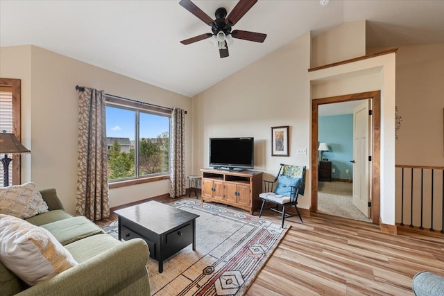 living area with baseboards, light wood-style flooring, ceiling fan, and high vaulted ceiling