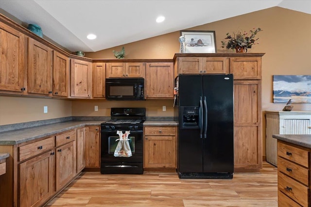 kitchen featuring brown cabinets, black appliances, vaulted ceiling, dark countertops, and light wood-style floors