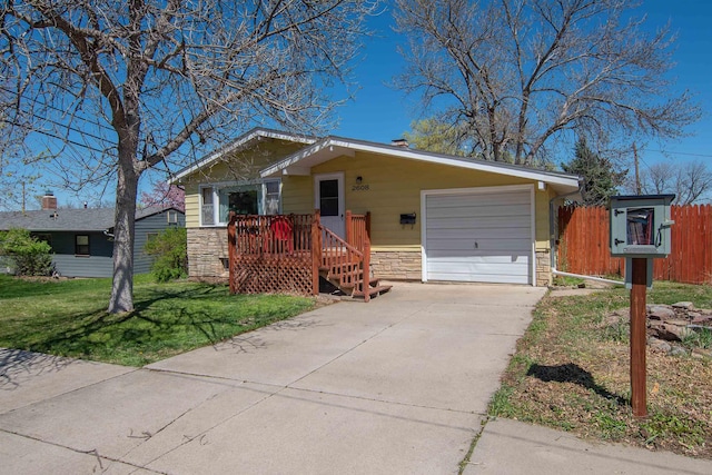 2608 Maple Ave, Rapid City, SD 57701 - view of front of house featuring a front yard, fence, an attached garage, concrete driveway, and stone siding