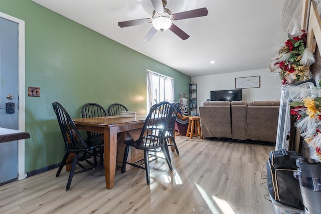dining room with a ceiling fan, light wood-style floors, and vaulted ceiling