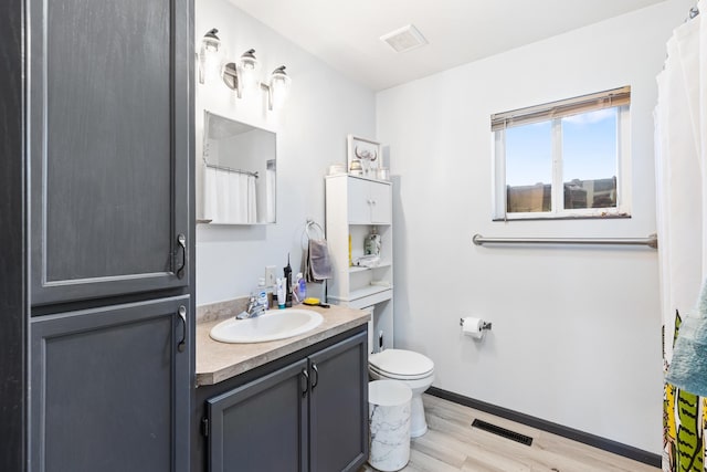 full bath featuring vanity, toilet, visible vents, and wood finished floors