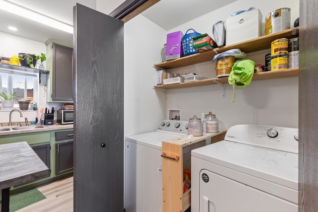 washroom featuring laundry area, independent washer and dryer, light wood-type flooring, and a sink