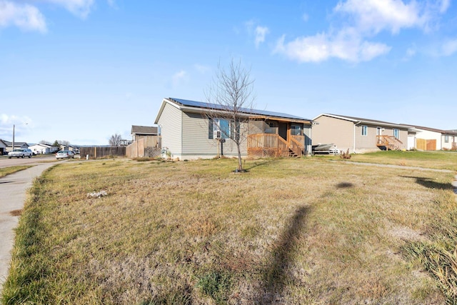 rear view of property featuring roof mounted solar panels, a yard, and a residential view