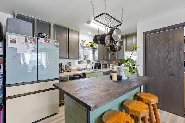 kitchen with a sink, a kitchen bar, wood counters, light wood-style floors, and appliances with stainless steel finishes