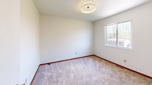 carpeted spare room featuring baseboards