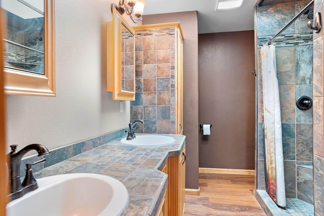1245 Pine Cone Ln, Rapid City, SD 57701 - bathroom with a tile shower, wood finished floors, and double vanity