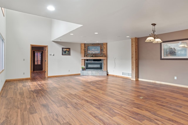 1245 Pine Cone Ln, Rapid City, SD 57701 - unfurnished living room featuring baseboards, recessed lighting, wood finished floors, a fireplace, and a chandelier