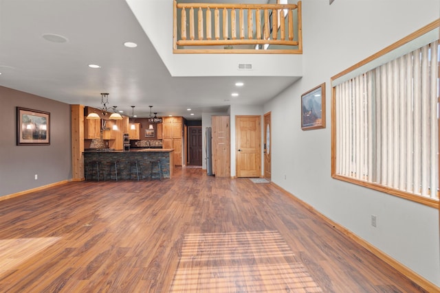 1245 Pine Cone Ln, Rapid City, SD 57701 - unfurnished living room featuring wood finished floors, baseboards, recessed lighting, a chandelier, and a towering ceiling
