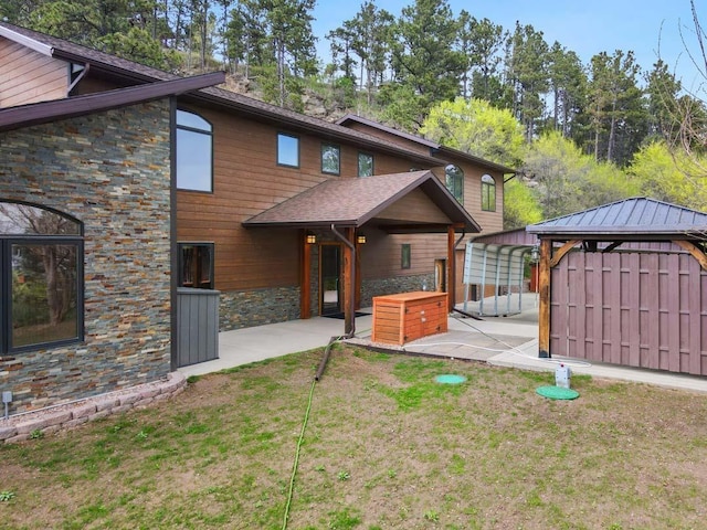 1245 Pine Cone Ln, Rapid City, SD 57701 - rear view of house with stone siding, a patio area, a gazebo, and a yard