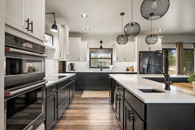 kitchen with black appliances, plenty of natural light, wood finished floors, a sink, and recessed lighting