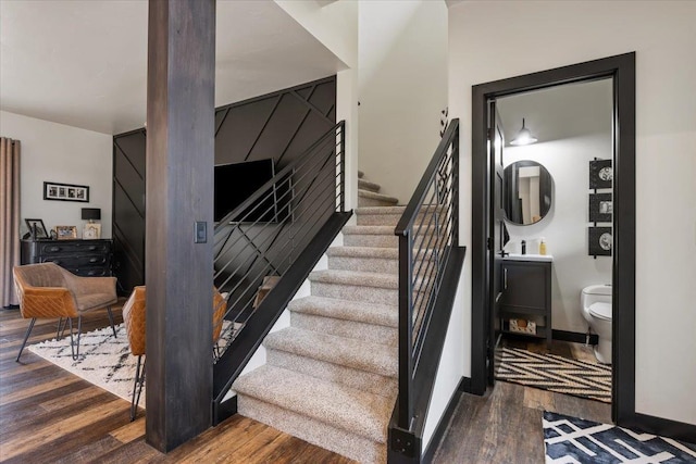 staircase featuring wood finished floors and baseboards