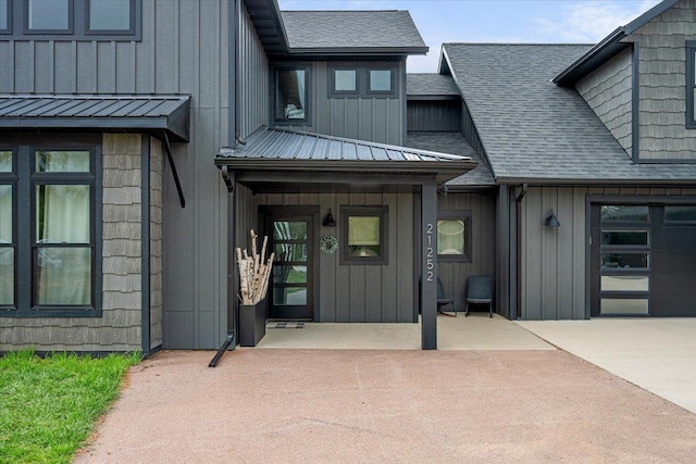 entrance to property with board and batten siding and a shingled roof