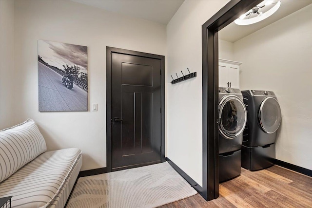 laundry area with cabinet space, light wood-style floors, separate washer and dryer, and baseboards