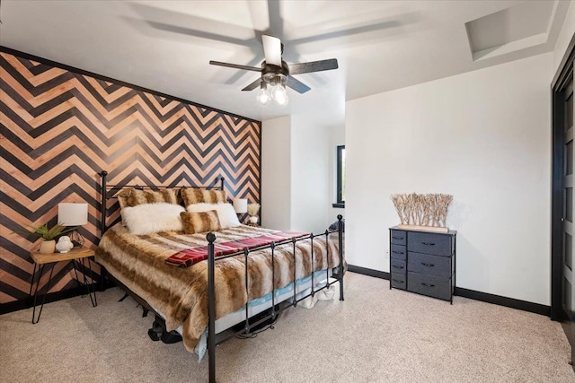 bedroom with baseboards, an accent wall, light carpet, and ceiling fan