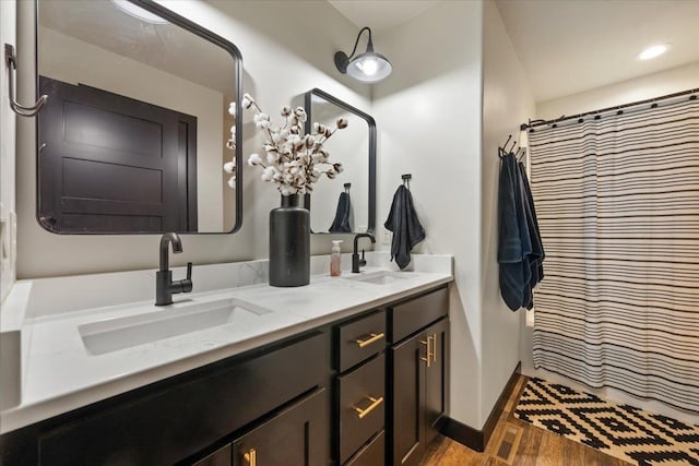 full bathroom with wood finished floors, double vanity, and baseboards