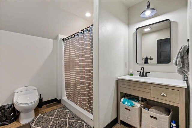 bathroom featuring wood finished floors, toilet, a shower with curtain, vanity, and baseboards