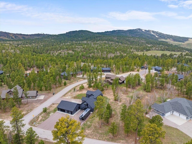 drone / aerial view of a heavily wooded area and a mountainous background