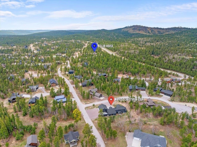 aerial view of property's location featuring a forest, a mountainous background, and nearby suburban area