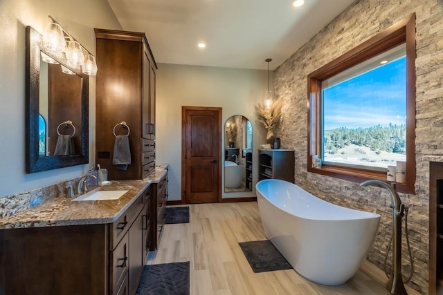bathroom featuring a soaking tub, vanity, wood finished floors, and recessed lighting