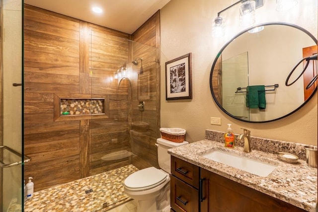 bathroom with a tile shower, toilet, and vanity