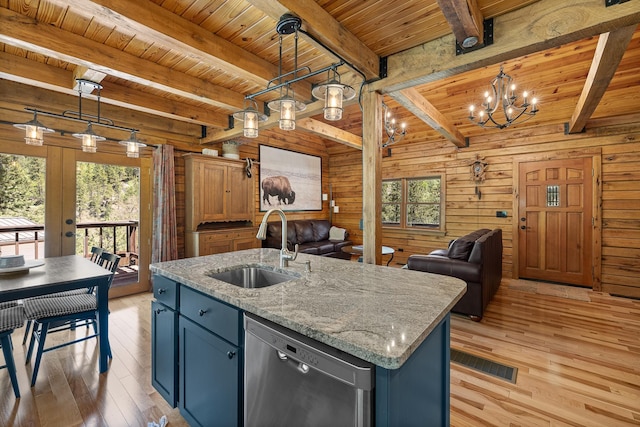kitchen with a sink, dishwasher, open floor plan, light wood-style flooring, and wooden walls