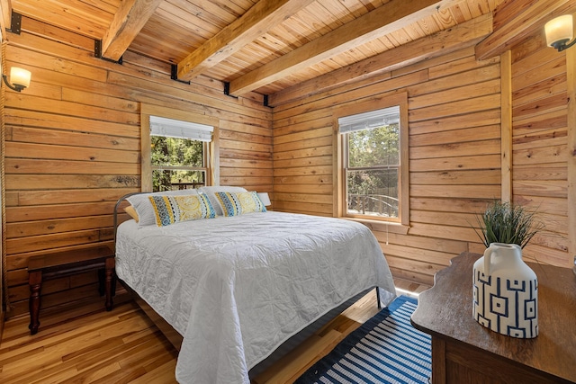 bedroom with wood ceiling, multiple windows, beamed ceiling, light wood-style flooring, and wood walls