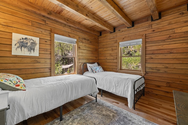 bedroom with wood ceiling, multiple windows, beamed ceiling, wood finished floors, and wood walls