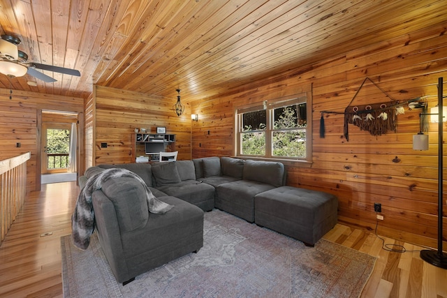 living room featuring wood ceiling, wood walls, ceiling fan, and light wood-type flooring