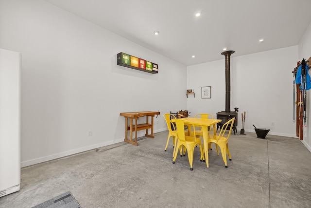dining room featuring a wood stove, concrete flooring, recessed lighting, and baseboards
