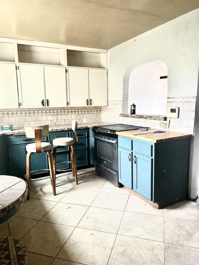 kitchen featuring decorative backsplash, arched walkways, light countertops, and white cabinetry