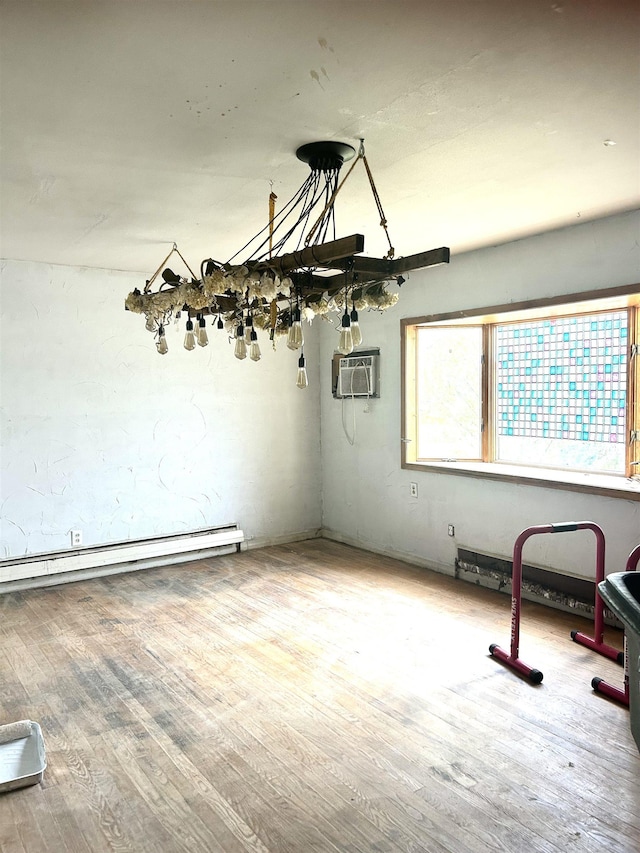 spare room featuring a baseboard heating unit, a wall mounted air conditioner, and wood finished floors