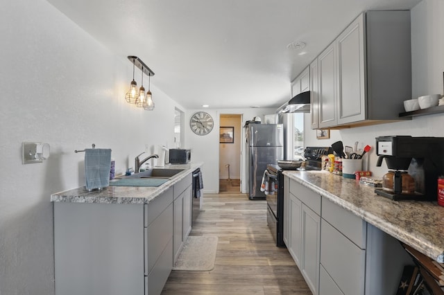 101 E Summit St, Lead, SD 57754 - kitchen with stainless steel appliances, a sink, under cabinet range hood, light wood-style flooring, and gray cabinetry