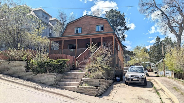 125 S Galena St, Lead, SD 57754 - view of front facade with stairs, a gambrel roof, dirt driveway, and a porch