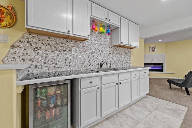 4103 Waterville Ct, Rapid City, SD 57702 - kitchen with beverage cooler, a sink, a premium fireplace, white cabinets, and tasteful backsplash