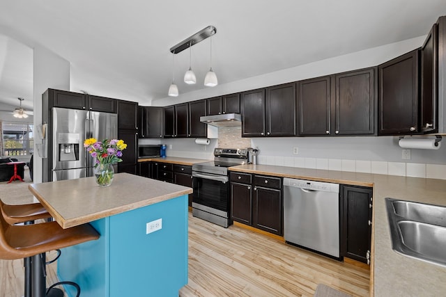 4103 Waterville Ct, Rapid City, SD 57702 - kitchen with appliances with stainless steel finishes, under cabinet range hood, vaulted ceiling, a kitchen bar, and light wood-style floors