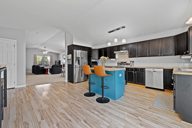 4103 Waterville Ct, Rapid City, SD 57702 - kitchen with appliances with stainless steel finishes, vaulted ceiling, light countertops, a center island, and under cabinet range hood