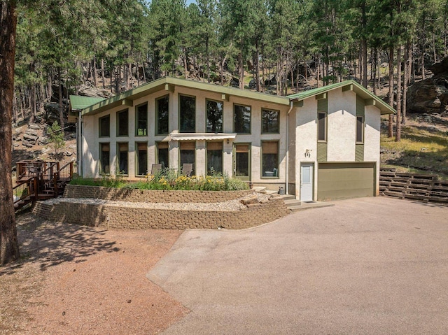 12990 Old Hill City Rd, Keystone, SD 57751 - mid-century modern home featuring stucco siding, a garage, and driveway