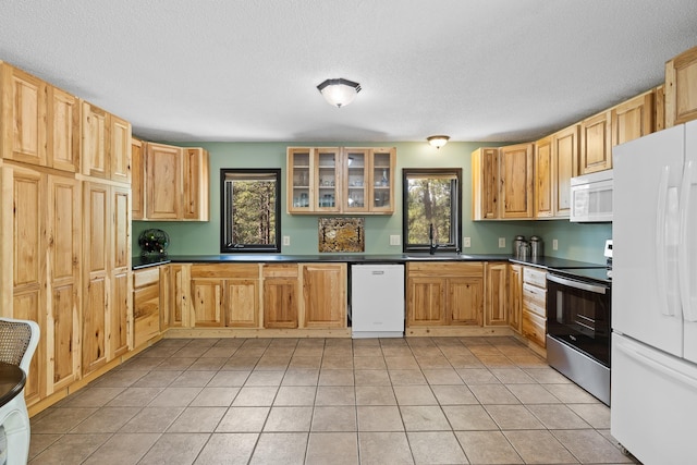 12990 Old Hill City Rd, Keystone, SD 57751 - kitchen with white appliances, dark countertops, light tile patterned floors, glass insert cabinets, and a textured ceiling
