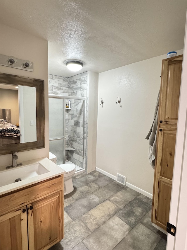 bathroom featuring a stall shower, a textured ceiling, vanity, toilet, and baseboards