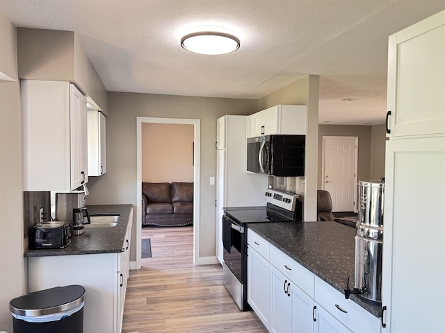 kitchen featuring stainless steel appliances, light wood-type flooring, white cabinets, baseboards, and a textured ceiling