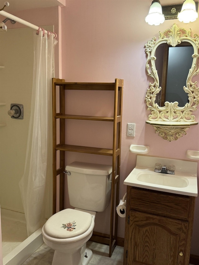 bathroom featuring toilet, a shower stall, vanity, tile patterned flooring, and baseboards