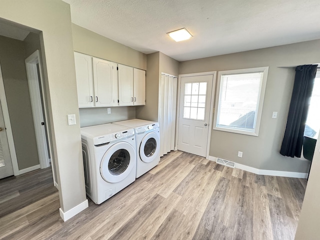 washroom featuring separate washer and dryer, light wood-style floors, baseboards, and cabinet space