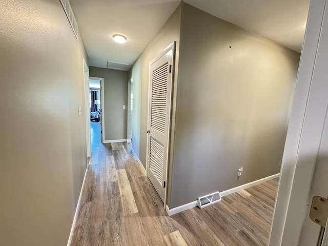 hall with wood finished floors, baseboards, and attic access
