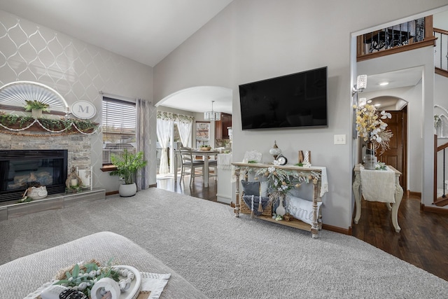 4127 Quiment Ct, Rapid City, SD 57702 - living area with arched walkways, wood finished floors, a stone fireplace, high vaulted ceiling, and baseboards