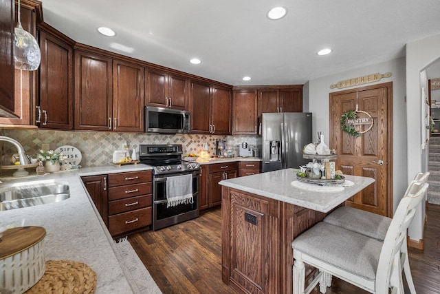 4127 Quiment Ct, Rapid City, SD 57702 - kitchen featuring appliances with stainless steel finishes, a sink, dark wood finished floors, tasteful backsplash, and a kitchen island
