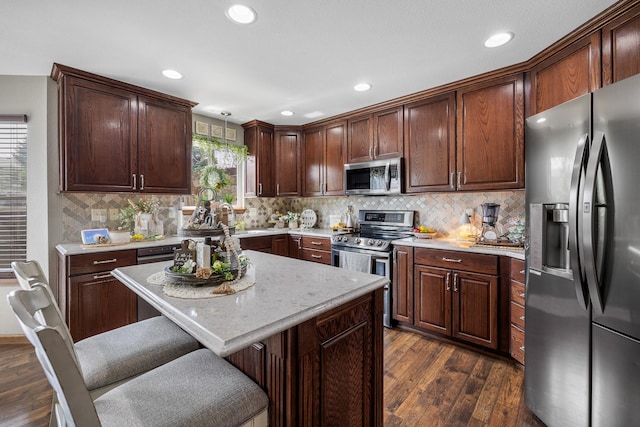 4127 Quiment Ct, Rapid City, SD 57702 - kitchen with appliances with stainless steel finishes, dark wood finished floors, a breakfast bar, decorative backsplash, and recessed lighting