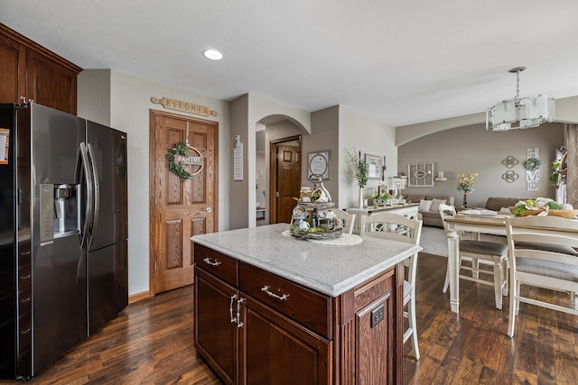 4127 Quiment Ct, Rapid City, SD 57702 - kitchen featuring refrigerator with ice dispenser, arched walkways, dark wood-type flooring, open floor plan, and a kitchen breakfast bar