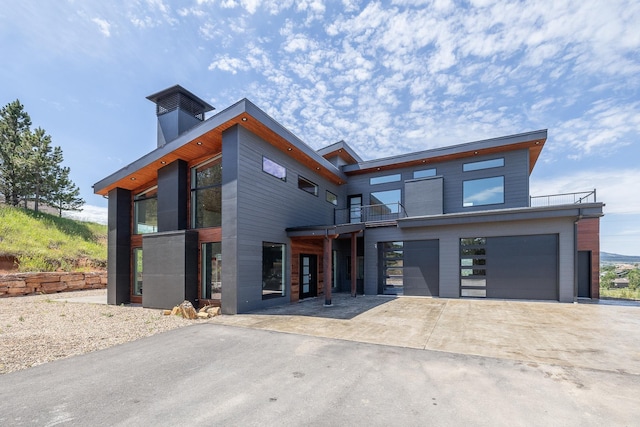 modern home with driveway, a balcony, and an attached garage