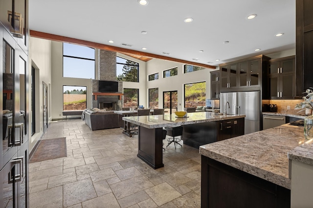 kitchen featuring stainless steel appliances, stone tile flooring, a kitchen island with sink, plenty of natural light, and recessed lighting
