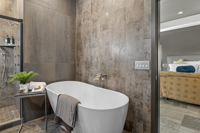 full bathroom with tile walls, a soaking tub, a tile shower, and ensuite bathroom